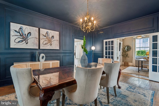 dining space featuring a chandelier, wood-type flooring, french doors, and crown molding