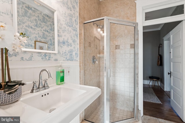 bathroom with crown molding, a shower with door, and sink