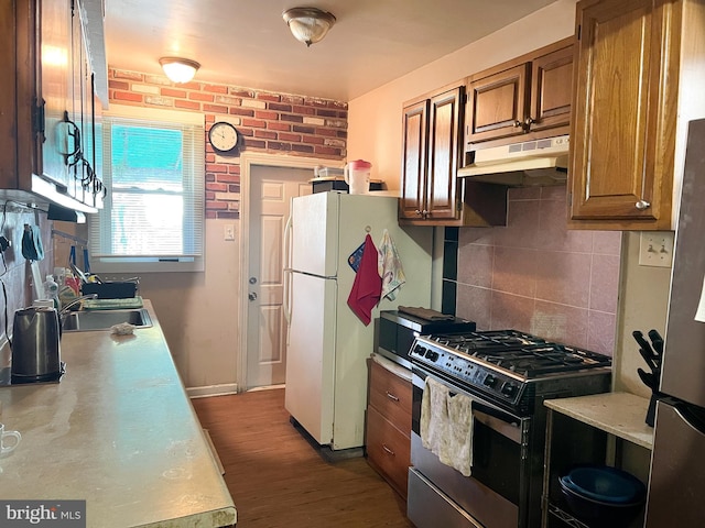 kitchen featuring sink, brick wall, white refrigerator, black range with gas cooktop, and decorative backsplash