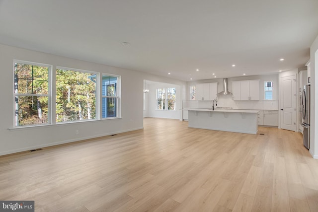 unfurnished living room featuring plenty of natural light, sink, and light hardwood / wood-style flooring