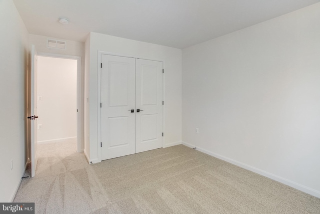 unfurnished bedroom with light carpet and a closet