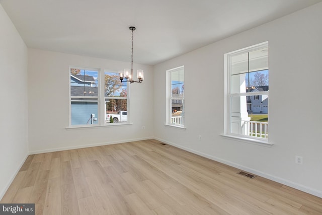 unfurnished dining area with a chandelier and light wood-type flooring