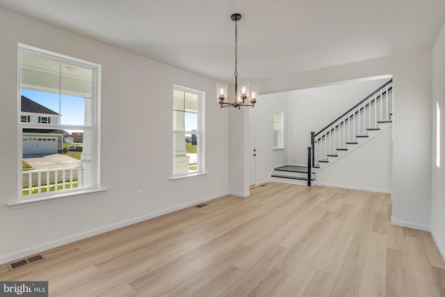 unfurnished dining area featuring light wood-type flooring and an inviting chandelier