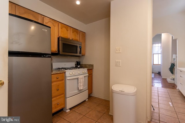 kitchen with light stone counters, appliances with stainless steel finishes, and light tile patterned floors