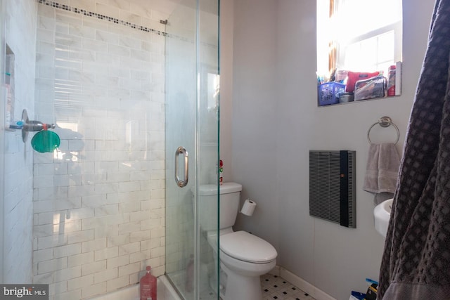 bathroom featuring tile patterned floors, toilet, and a shower with shower door