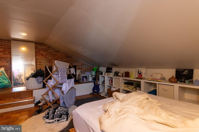 bedroom with parquet floors, lofted ceiling, and brick wall