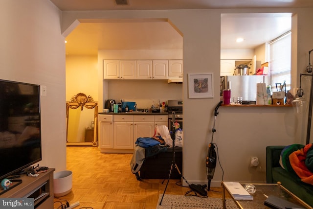 kitchen with white cabinetry, stainless steel gas range, fridge, and light parquet flooring