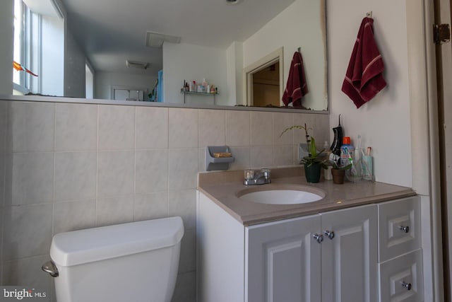 bathroom with vanity, toilet, tile walls, and backsplash