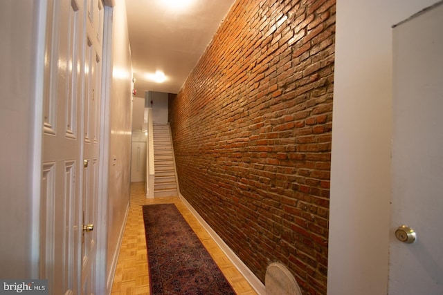 hall featuring parquet floors and brick wall