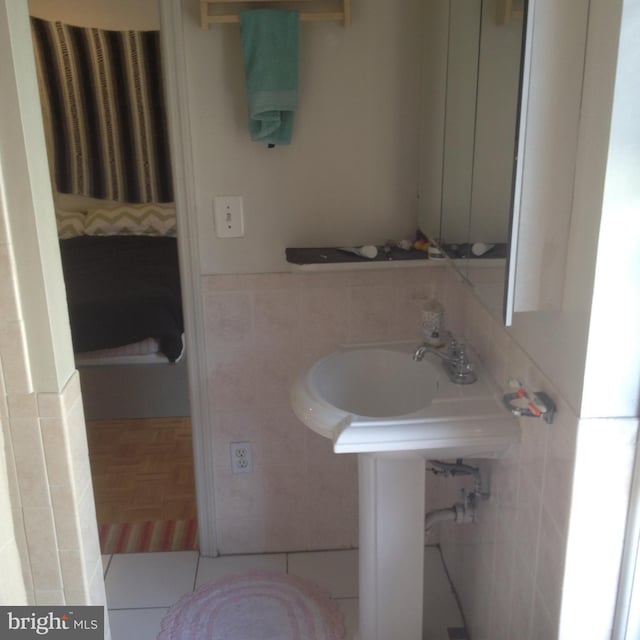 bathroom with tile patterned flooring, sink, and tile walls