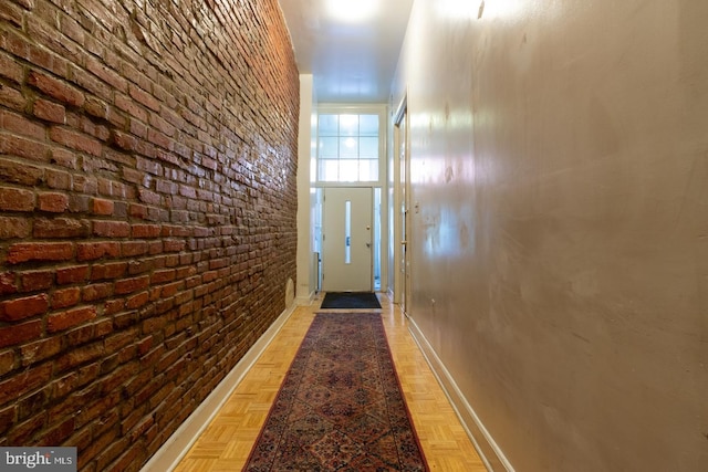 doorway to outside with light parquet flooring and brick wall