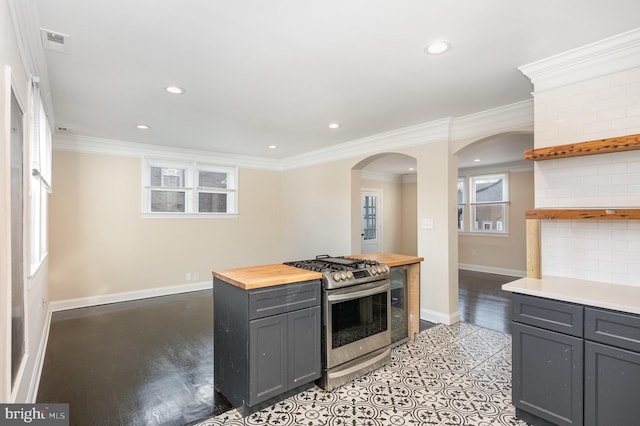 kitchen with gray cabinetry, wood counters, stainless steel gas range, crown molding, and decorative backsplash