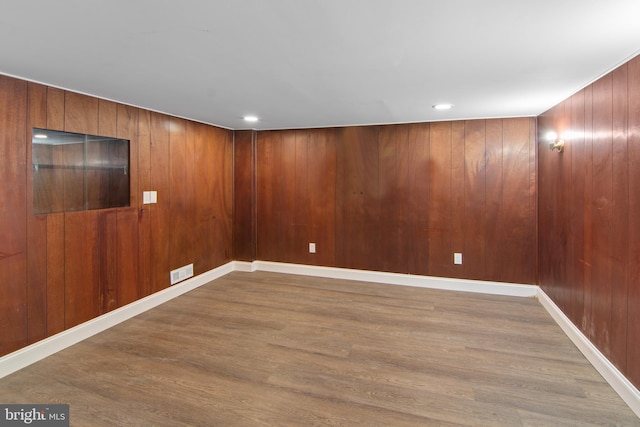 empty room with wood-type flooring and wood walls