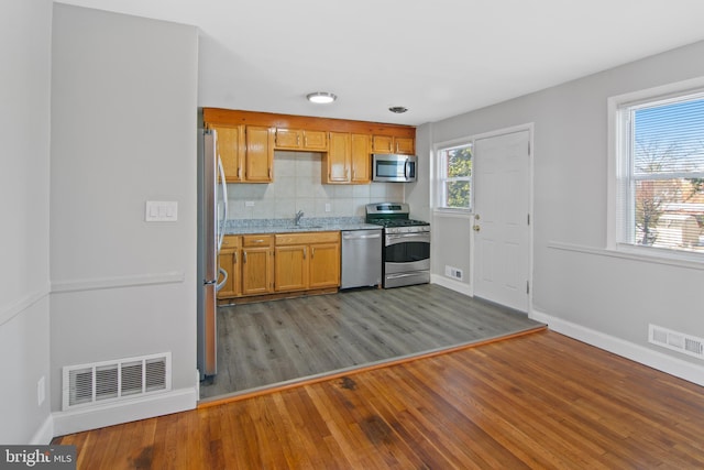 kitchen with tasteful backsplash, sink, stainless steel appliances, and light wood-type flooring