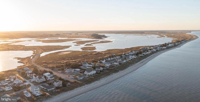 aerial view at dusk featuring a water view and a beach view