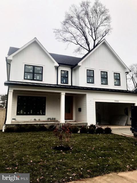 modern farmhouse style home with a porch, a front yard, and a garage