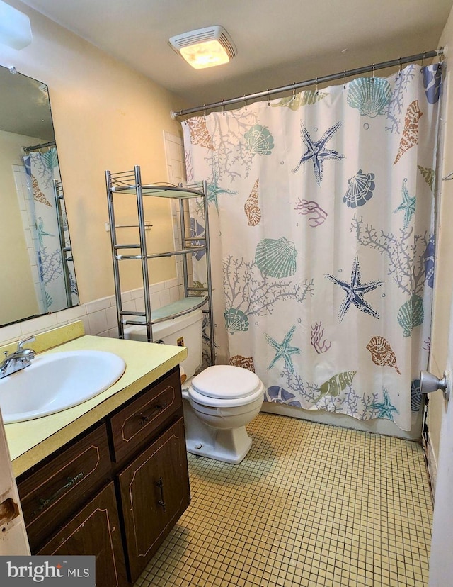 bathroom featuring curtained shower, tile patterned flooring, vanity, and toilet