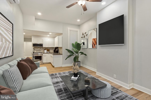 living room with ceiling fan, light wood-type flooring, and sink