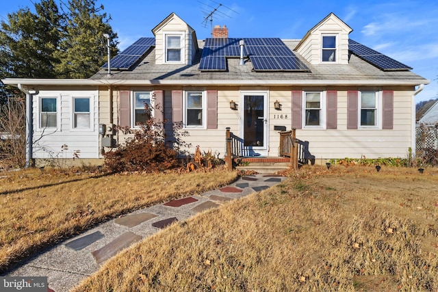 cape cod home featuring solar panels