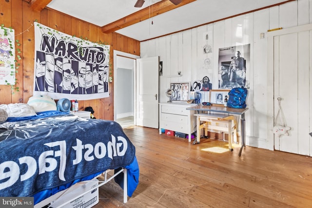 bedroom featuring ceiling fan, hardwood / wood-style floors, beamed ceiling, and wood walls