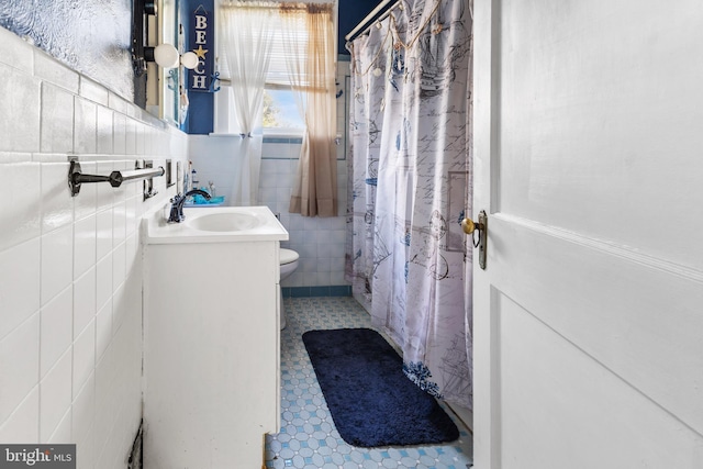 bathroom with vanity, toilet, and tile walls