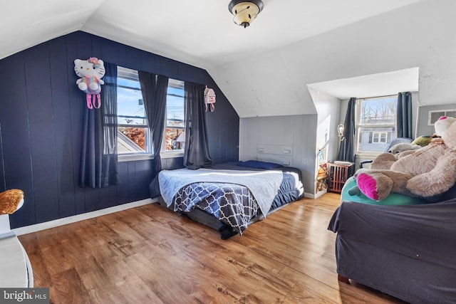 bedroom featuring wood-type flooring, vaulted ceiling, and multiple windows