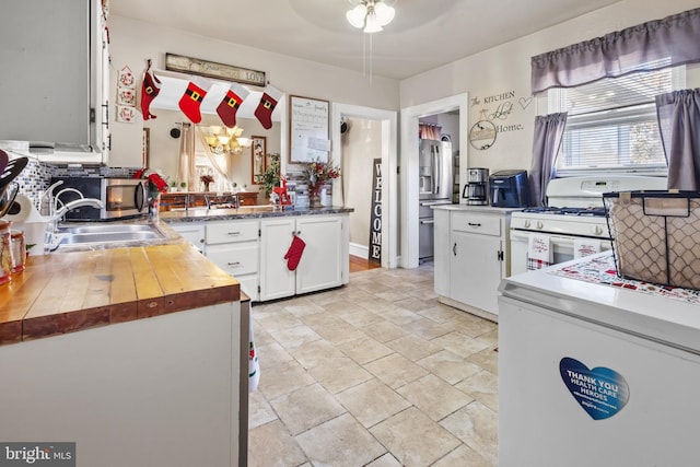 kitchen featuring appliances with stainless steel finishes, backsplash, sink, an inviting chandelier, and white cabinetry