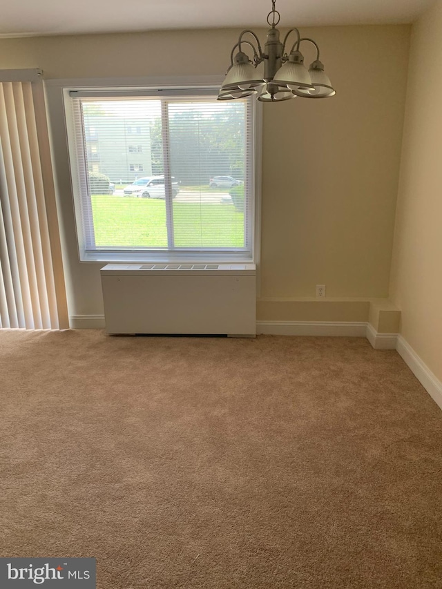 carpeted spare room featuring an inviting chandelier