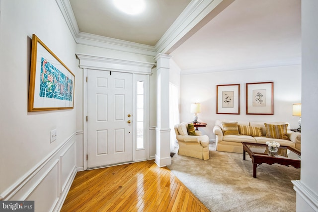 entryway with light hardwood / wood-style floors, ornate columns, and crown molding