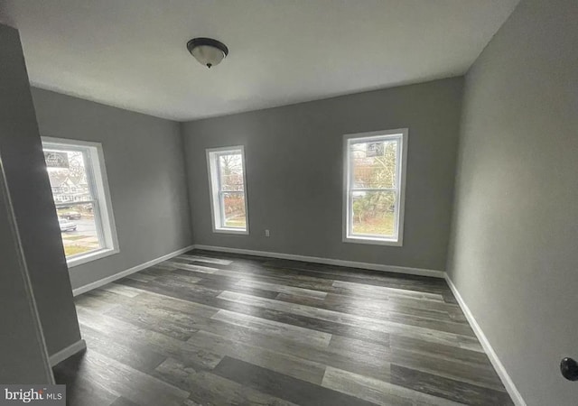 empty room featuring plenty of natural light and dark wood-type flooring