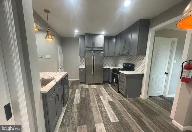 kitchen with backsplash, dark hardwood / wood-style floors, gray cabinets, and stainless steel appliances