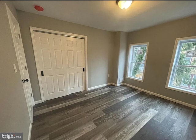 unfurnished bedroom with dark wood-type flooring and a closet