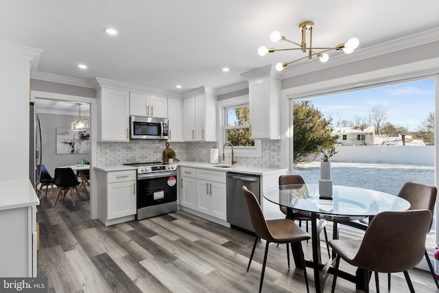 kitchen with white cabinets, appliances with stainless steel finishes, tasteful backsplash, and pendant lighting