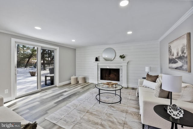 living room featuring a fireplace, ornamental molding, light hardwood / wood-style flooring, and wooden walls