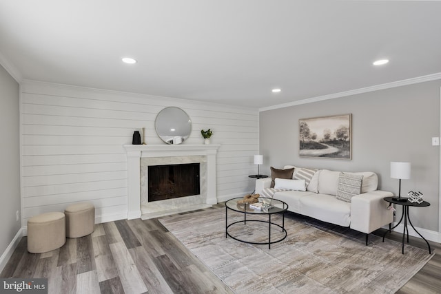 living room featuring hardwood / wood-style flooring, wooden walls, crown molding, and a high end fireplace