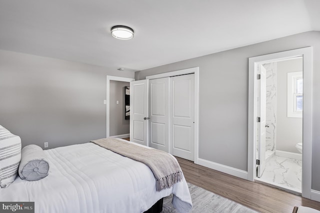 bedroom with hardwood / wood-style flooring, a closet, and ensuite bath