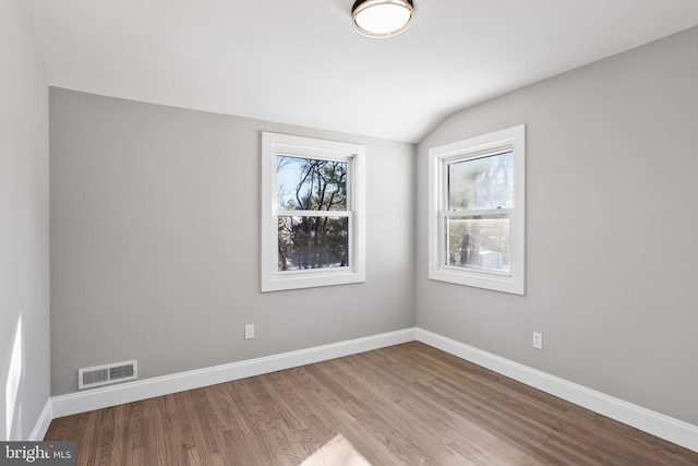 unfurnished room with light hardwood / wood-style floors and lofted ceiling