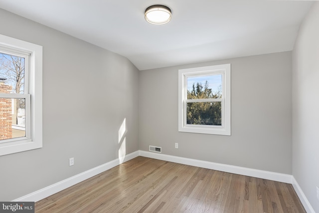 spare room with lofted ceiling and light hardwood / wood-style flooring