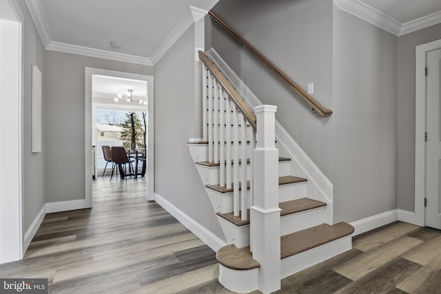 stairs with hardwood / wood-style floors, a notable chandelier, and ornamental molding