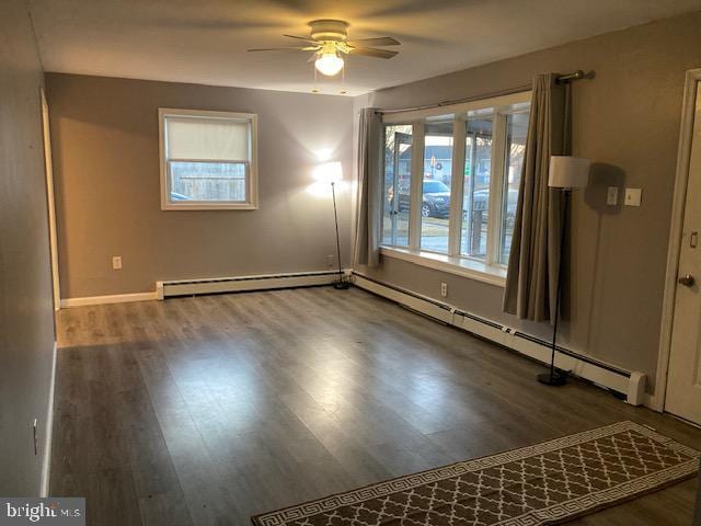 spare room with baseboard heating, ceiling fan, and dark hardwood / wood-style flooring