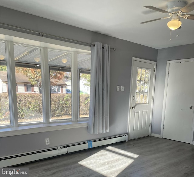 entryway with a wealth of natural light, ceiling fan, dark hardwood / wood-style floors, and a baseboard heating unit