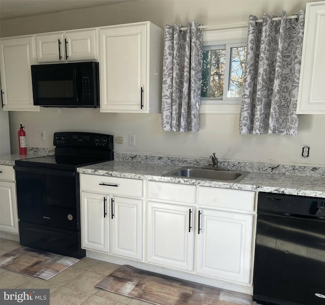 kitchen with black appliances, sink, light stone countertops, light tile patterned flooring, and white cabinetry