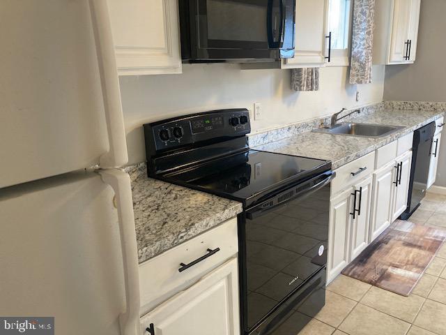 kitchen with black appliances, white cabinets, and sink