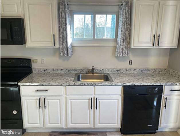 kitchen with sink, white cabinets, and black appliances