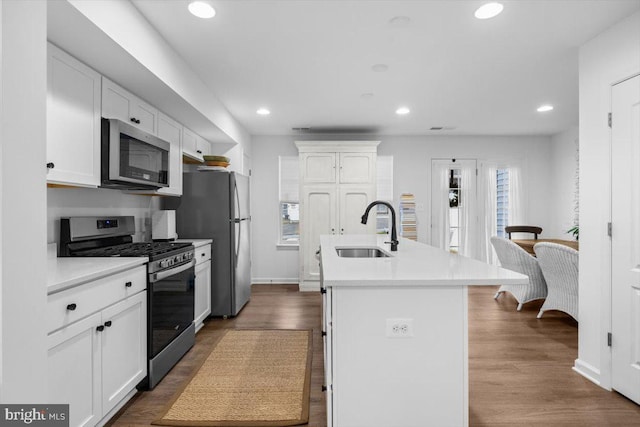 kitchen featuring white cabinets, sink, dark hardwood / wood-style floors, an island with sink, and appliances with stainless steel finishes