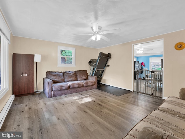 living room featuring ceiling fan, a healthy amount of sunlight, light hardwood / wood-style floors, and baseboard heating