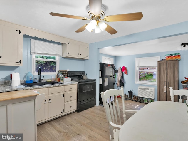 kitchen featuring a wall unit AC, ceiling fan, sink, light hardwood / wood-style flooring, and black range with electric stovetop