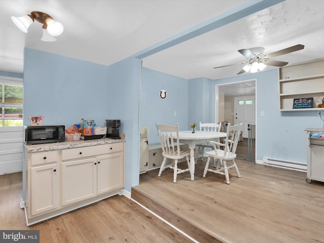 kitchen featuring light stone countertops, light wood-type flooring, ceiling fan, a baseboard heating unit, and white cabinetry