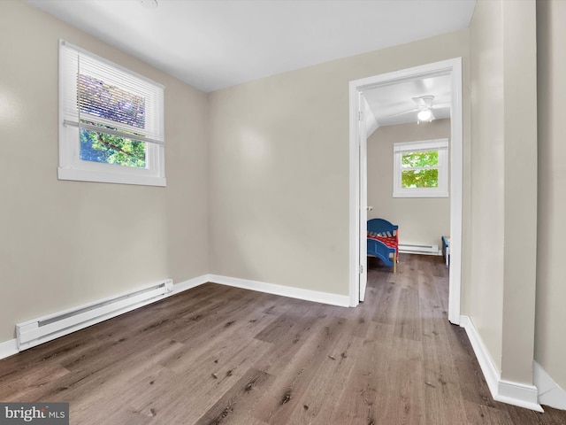 spare room featuring vaulted ceiling, light hardwood / wood-style flooring, ceiling fan, and a baseboard heating unit