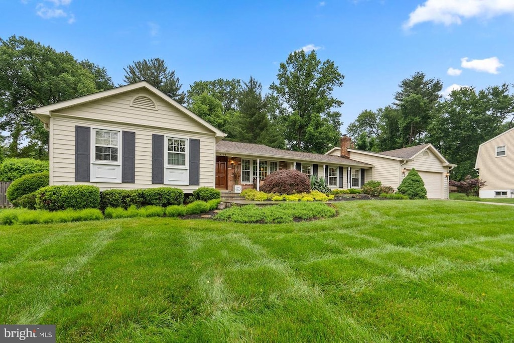 ranch-style home featuring an attached garage, a chimney, and a front yard